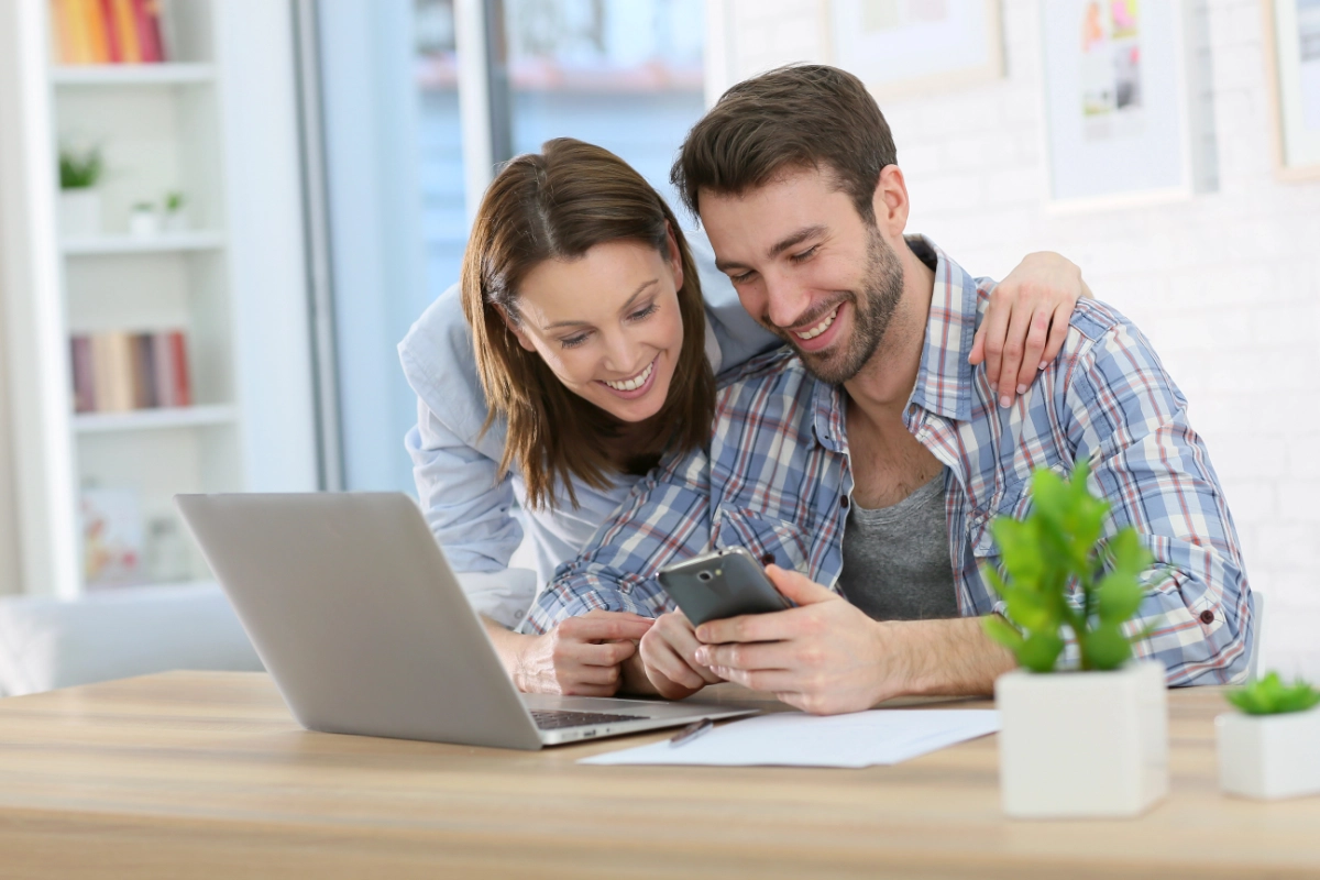 Lebenssituationsplanung mit simple tax finance Junges Paar schaut auf Smartphone und Laptop